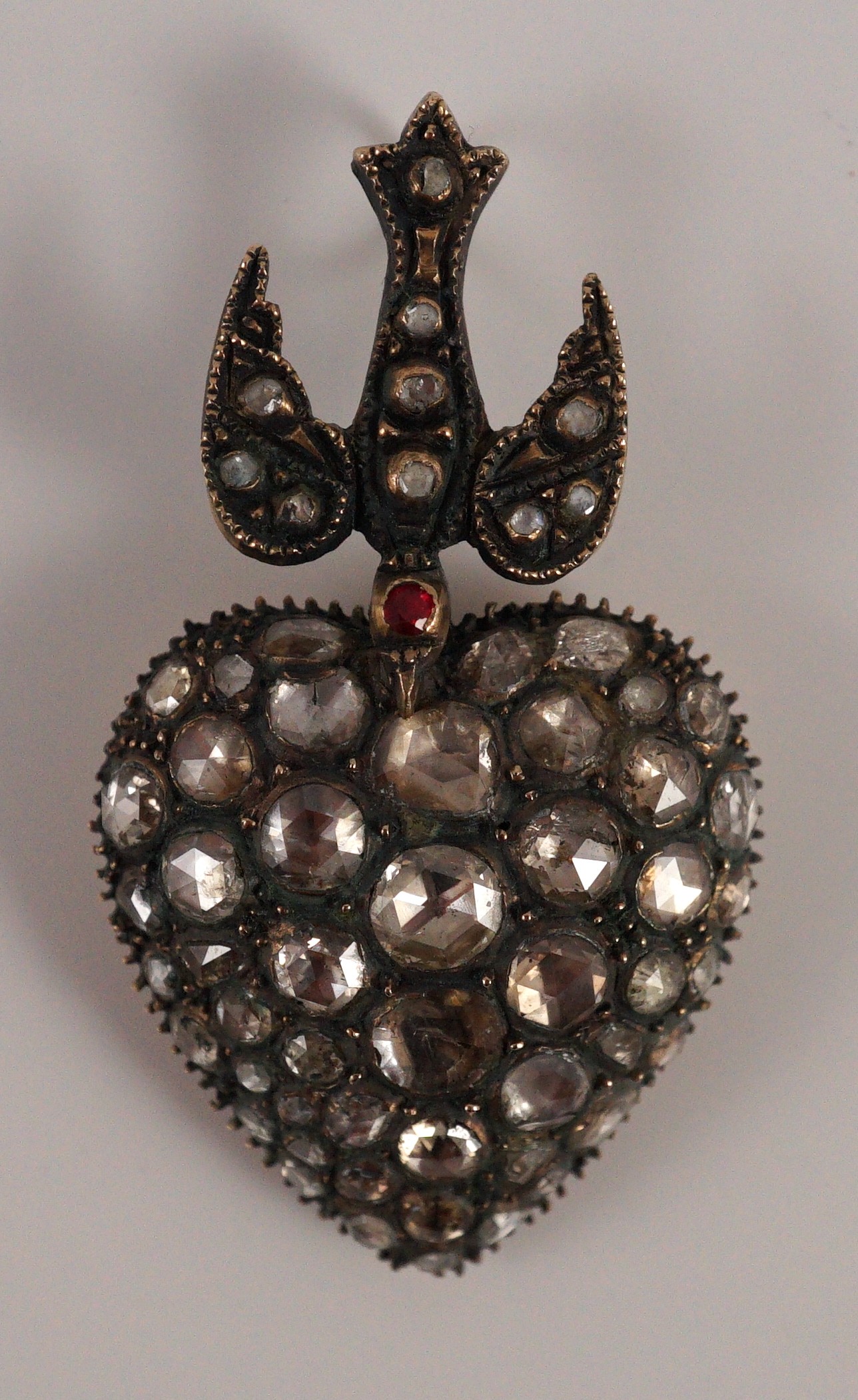 A Victorian style gold and graduated rose cut diamond set heart shaped pendant, with diamond and spinel? set bale modelled as a swallow
